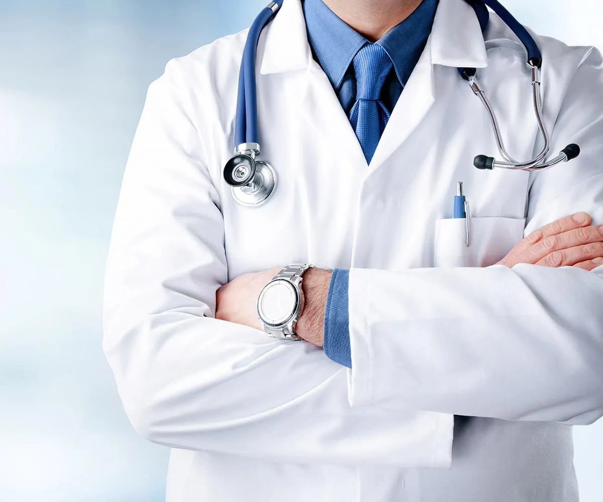 Un medico in camice con lo stetoscopio, a braccia conserte