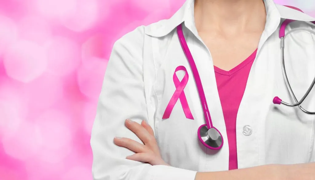 Una dottoressa in camice con il nastro rosa della prevenzione del tumore al seno